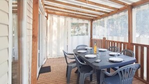Eine überdachte Terrasse mit einem Tisch für vier Personen, umgeben von Stühlen.