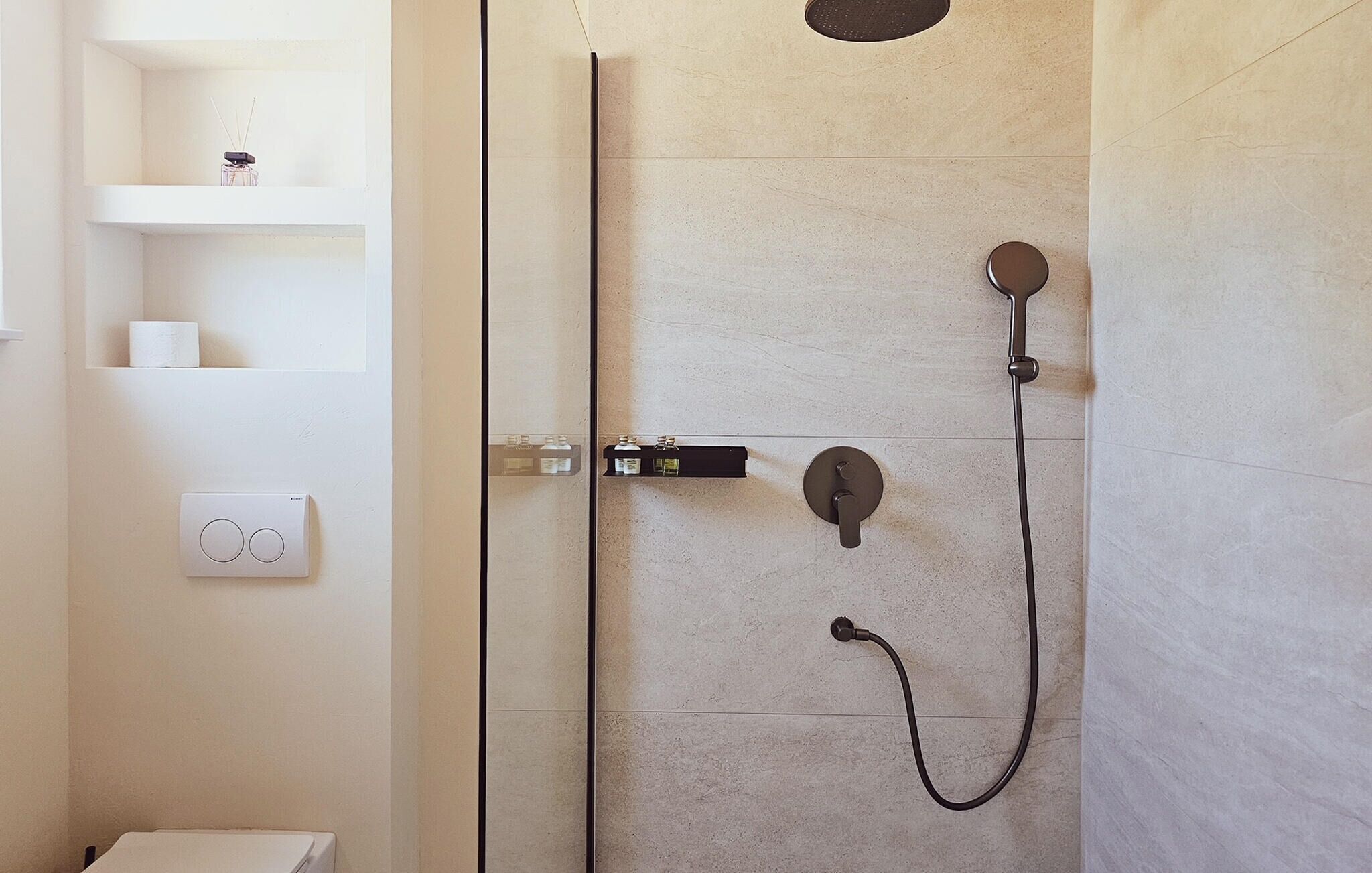 Een moderne douche met een handdouche en een douchekop aan de muur.