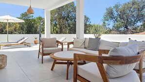 A covered outdoor seating area with wooden furniture and white cushions, overlooking a natural landscape. - Luxurious home in Zman (Zman)