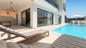 A modern poolside area with lounge chairs and a glass-enclosed patio. - Luxurious home in Zman (Zman)