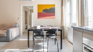Ein modernes Wohnzimmer mit Essbereich, einer Couch und einem Gemälde an der Wand.