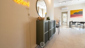 Ein modernes Interieur mit einer Neonreklame, einem großen Spiegel, einem Schrank und einem Essbereich.