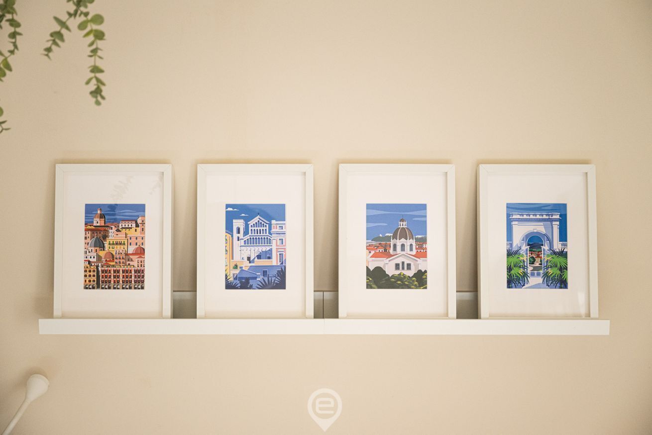 Four framed artworks on a wall, each depicting different architectural scenes.