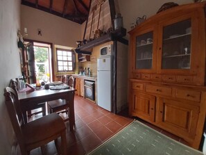 A kitchen with a dining table, chairs, a refrigerator, and a wooden cabinet with glass doors. - Villa-sleeps4-parking-garden-pool-nearairport (San Cristóbal de La Laguna)