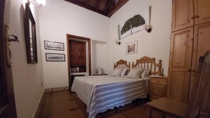 A bedroom with a bed, a wooden wardrobe, a chair, and a small table.