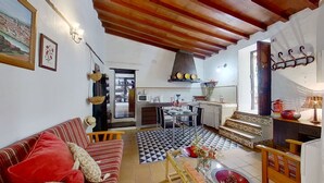 A cozy living room with a sofa, a dining area with a table and chairs, a kitchen with a stove and cabinets, and a staircase leading to an upper level. - Remarkable 4-bed Villa (San Cristóbal de La Laguna)