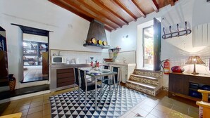 A compact kitchen with a microwave, sink, and dining area. There is a patterned rug on the floor and a small staircase leading to a balcony. - Remarkable 4-bed Villa (San Cristóbal de La Laguna)