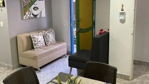 Een eethoek met een tafel, stoelen, een bank en een schilderij aan de muur.