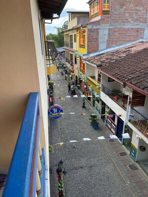 A narrow street with buildings on both sides, a sign for a supermarket, and a blue railing. - GUATAPE PARK APARTMENT (Guatapé)
