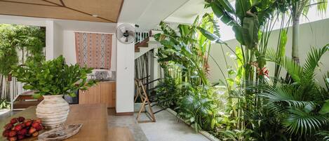 A spacious room with a wooden dining table, a large potted plant, and a staircase leading to an upper level.
