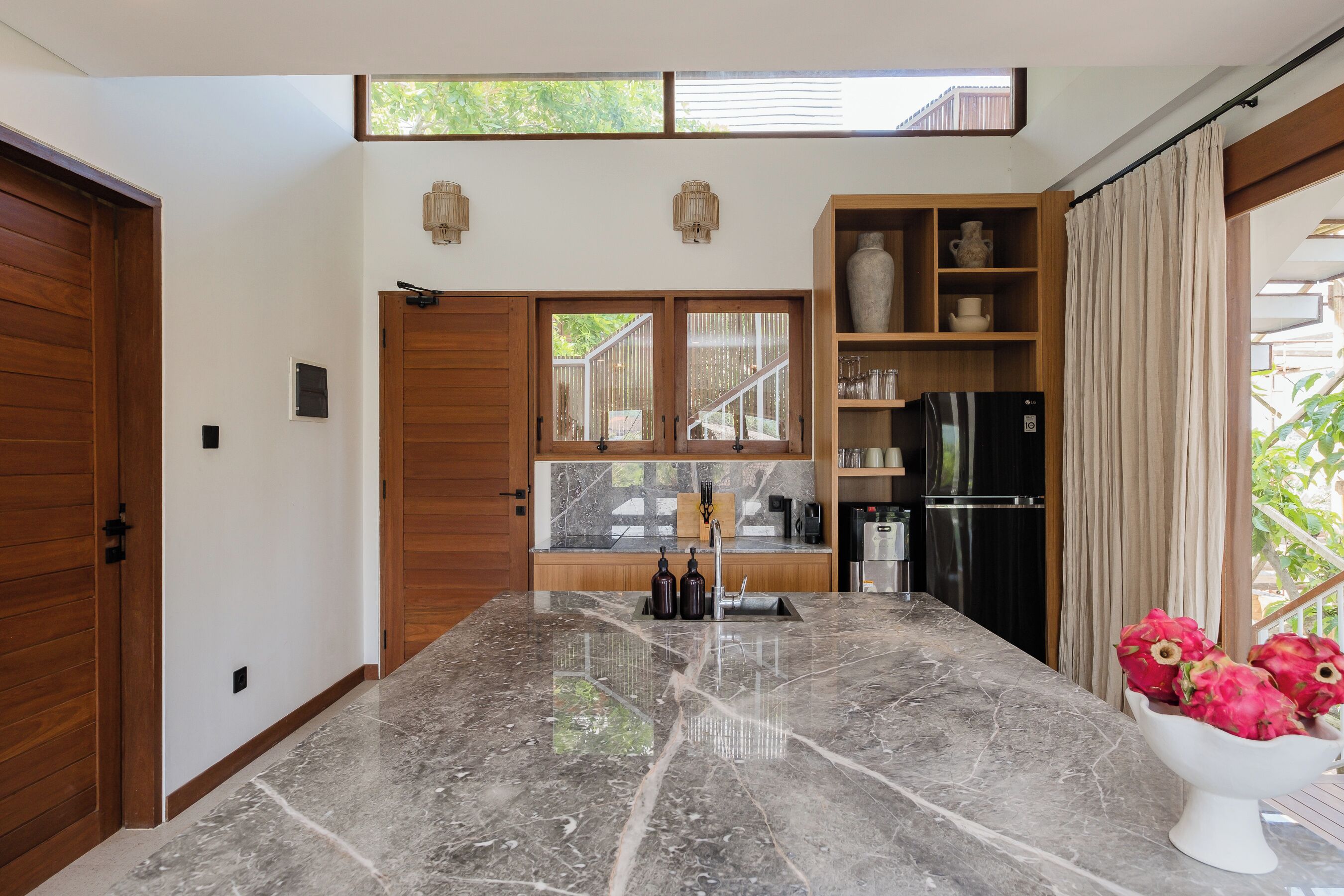Una cocina moderna con encimera de mármol, armarios de madera y horno integrado.