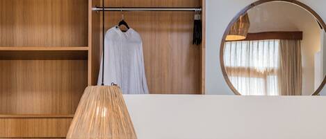 A bedroom with a wooden headboard, a bedside lamp, a round mirror, and a small round table with a plant.