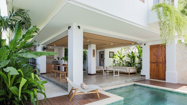 A pool area with a lounge chair, wooden deck, and indoor seating. - Treetop Villas (Pecatu)