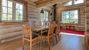 Ein rustikales Blockhaus-Interieur mit Esstisch, Stühlen und einer Bank.