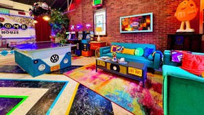 Ein lebhafter Spielsalon mit Neonreklame, einem Kicker und farbenfroher Sitzgelegenheiten.