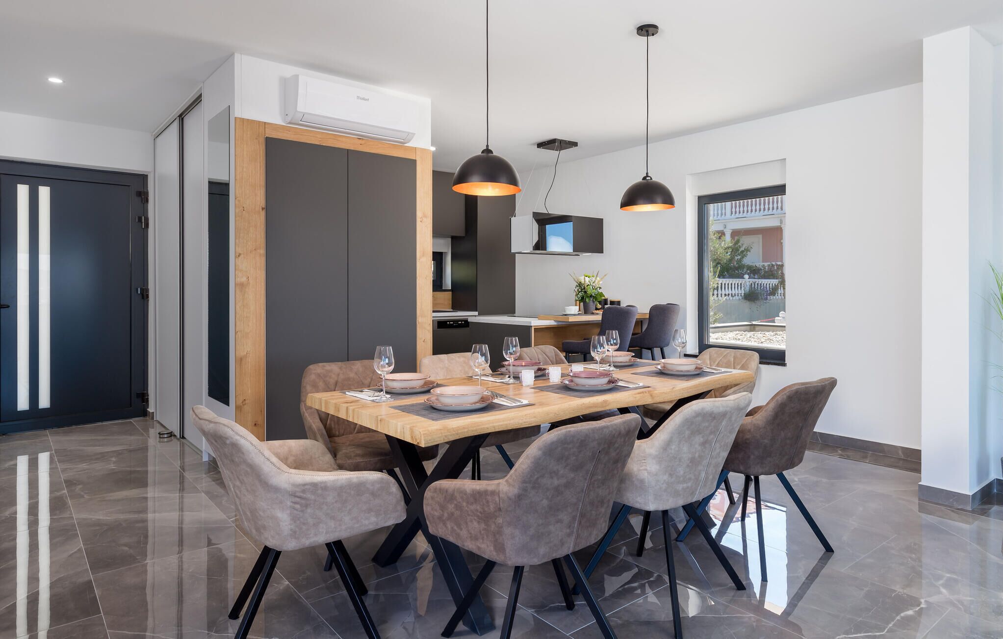 Een moderne eethoek met een grote tafel, zes stoelen en hanglampen.