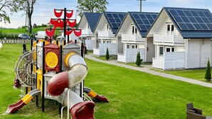 A playground with slides and swings, surrounded by houses with solar panels. - Gorgeous home in Sarbinowo with WiFi (Sarbinowo)