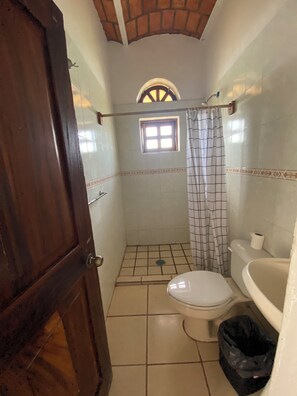 A small bathroom with a toilet, a shower area, and a window. - Bungalows Isla bonita (Rincón de Guayabitos)
