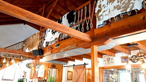 A rustic interior with exposed wooden beams, a cowhide wall, and a rustic chandelier.