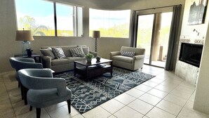 A living room with a sofa, two armchairs, a coffee table, and a fireplace.