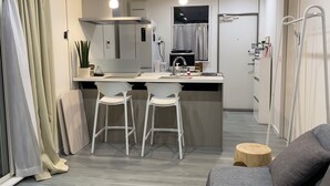 Une cuisine moderne avec des tabourets de bar blancs, un îlot central et des luminaires suspendus.