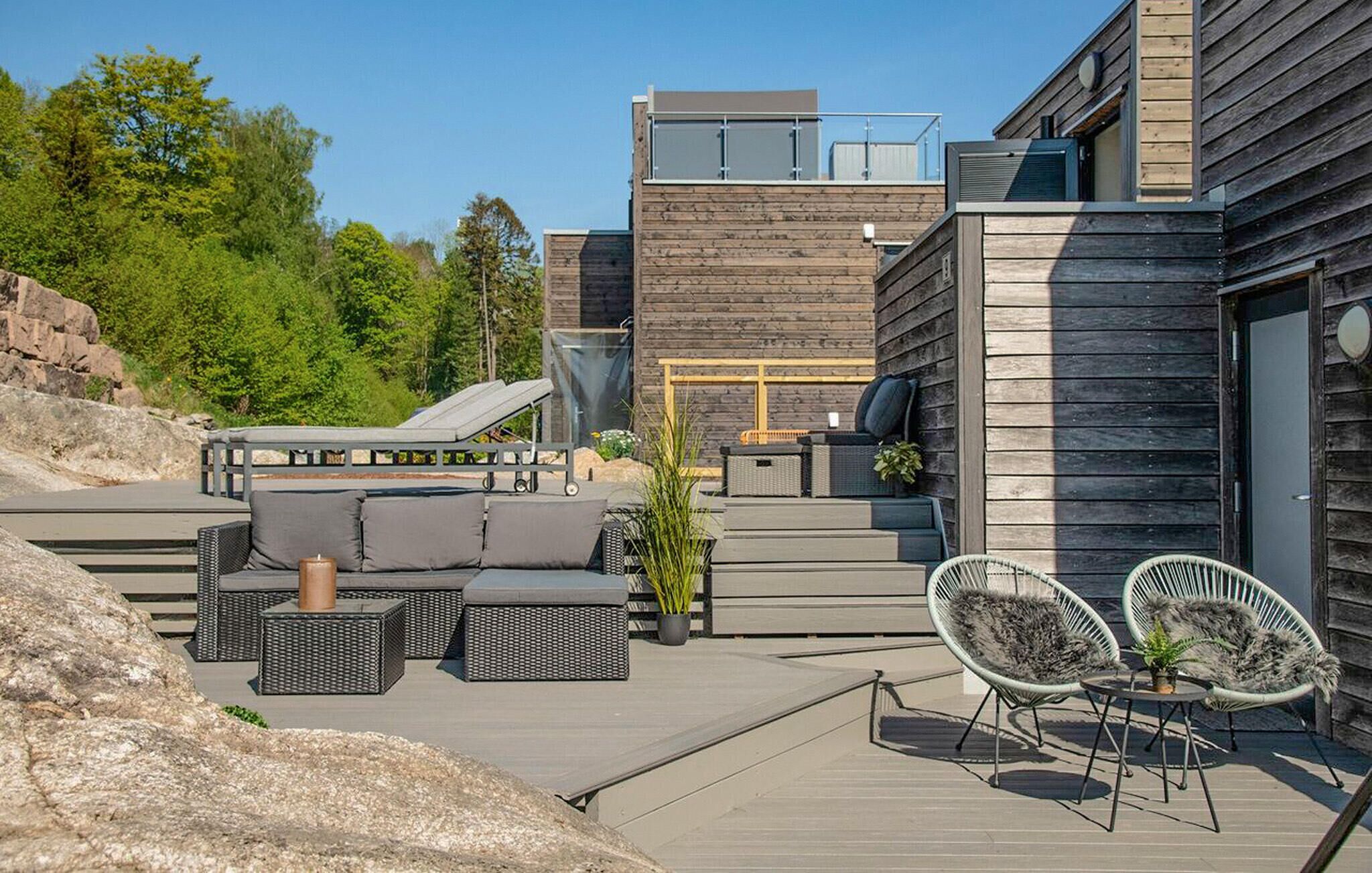 A modern outdoor patio with a sofa, chairs, and a small table.