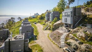 A modern residential area with multiple houses, a dirt road, and a view of the sea. - 4 bedroom nice home in Sætre (Sætre)