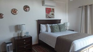 A neatly arranged hotel room with a bed, bedside tables, a lamp, and decorative wall pieces. - Cabañas hermosa vista Oceano-Montaña (Ensenada)
