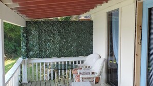 A covered porch with a glass table and wicker chairs, a stone wall, and a sliding glass door. - Charming 2-bedroom cottage in wonderful Newburg with WiFi, AC (Newburg)