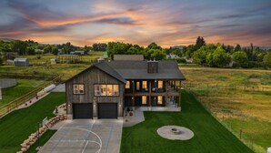 A large, rustic barn-style house with a spacious front yard, a basketball court, and a well-maintained lawn. - Modern Lakehouse l Slps 34 l Courts + Chefs Kitchen l Bear Lake Haven (Saint Charles)