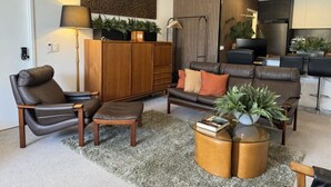 A modern living room with leather sofas, a wooden coffee table, and a large abstract painting.