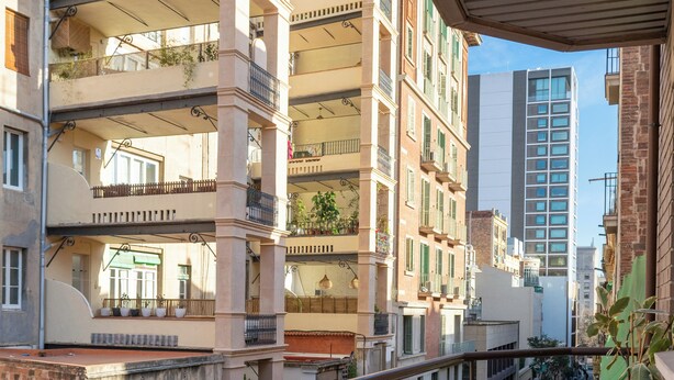 A balcony with a metal railing, a wooden bench, and potted plants.