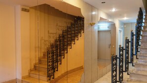 A grand staircase with ornate black railings and a glass barrier on one side.