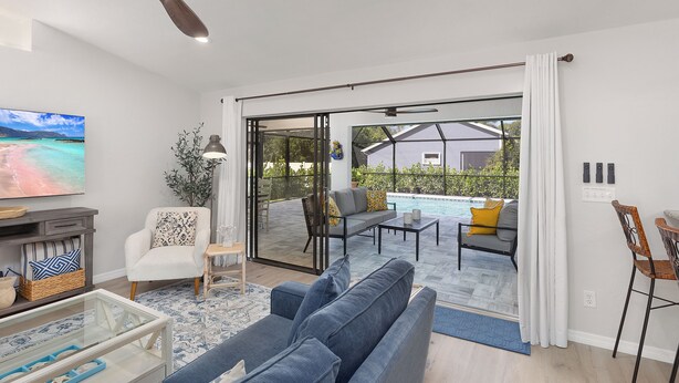 Una sala de estar moderna con sofá, sillón, mesa de centro, televisor y ventilador de techo.
