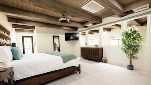 Een slaapkamer met een houten bed, een televisie, een dressoir en een kamerplant.