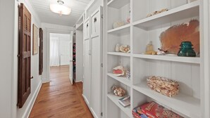 A hallway with white shelving units, wooden doors, and a ceiling fan. - New List - Heated Pool Golf Cart Bikes Sleeps 12 (Santa Rosa Beach)