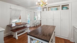 A kitchen with white cabinetry, a wooden table, and a chandelier. - New List - Heated Pool Golf Cart Bikes Sleeps 12 (Santa Rosa Beach)