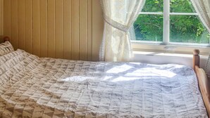 A bed with a patterned bedspread, wooden headboard, and a window with a view of greenery. - Stunning home in Tonstad with WiFi (Tonstad)