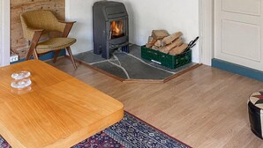 A cozy room with a wood-burning stove, a wicker chair, a wooden table, and a rug. - Stunning home in Tonstad with WiFi (Tonstad)