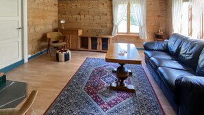 A cozy living room with a wooden interior, a black leather sofa, a wooden coffee table, a patterned rug, a small wooden cabinet, and a chair. - Stunning home in Tonstad with WiFi (Tonstad)