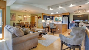 A modern kitchen with a central island, bar stools, and a dining area with a wooden table and chairs.