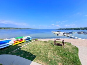 Une vue sur le lac, avec une zone herbeuse, une balançoire et des kayaks colorés amarrés au port de plaisance.