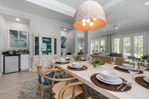 A spacious dining area with a long table set for six, surrounded by chairs.