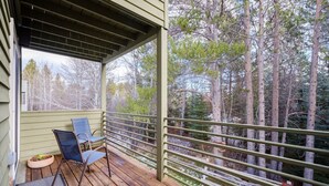 A wooden deck with two chairs and a small planter, overlooking a forested area. - RMR: Windflower 2121 Condo in The Aspens/Wilson,WY (Wilson)
