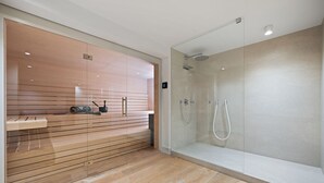 A modern bathroom with a glass shower enclosure, wooden flooring, and a built-in bench with storage. - Dünen.Way, Germany (List auf Sylt)
