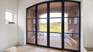 A room with a large sliding glass door leading to an outdoor deck with chairs.