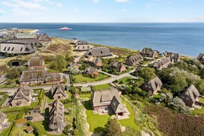 A coastal village with traditional houses, a marina, and a ship in the distance. - Heide.Way, Germany (List auf Sylt)