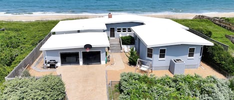 A two-story house with a garage, a basketball hoop, and a view of the ocean.