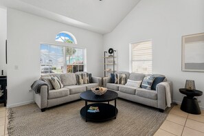 A modern living room with a sectional sofa, a round coffee table, and a bookshelf.