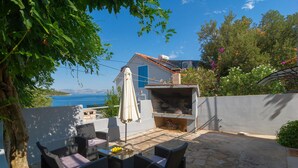 An outdoor patio with wicker furniture, a barbecue grill, and a view of the sea. - 1 bedroom gorgeous apartment in Necujam (Necujam)